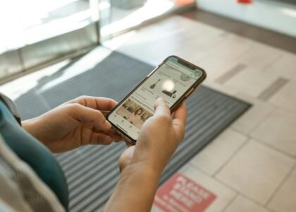 Close-up of hands holding a smartphone displaying an online shopping app in an indoor setting.