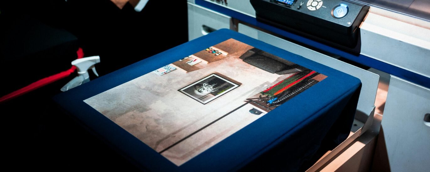 Close-up of a professional printer printing a custom artwork design on fabric in a studio setting.