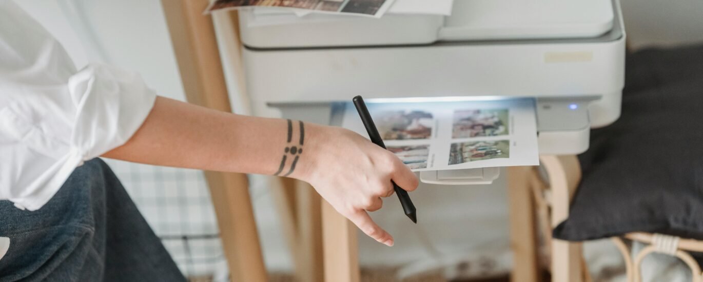 A woman using a stylus with a printer in a home office setting.