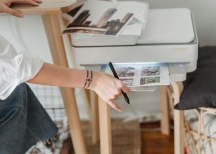 A woman using a stylus with a printer in a home office setting.